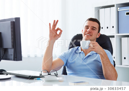 Young man drinking coffee in the office Young man drinking coffee in the office 30633457