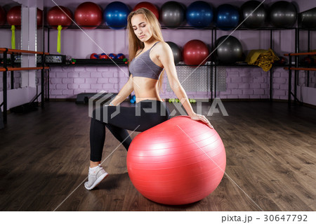 Young beautiful fitness girl sitting on red ball 30647792