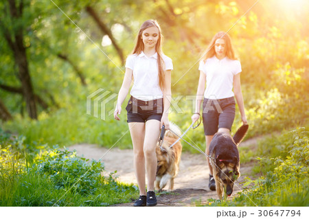 Two teenage girls walking with her dogs in park Two teenage girls walking with her dogs in park 30647794