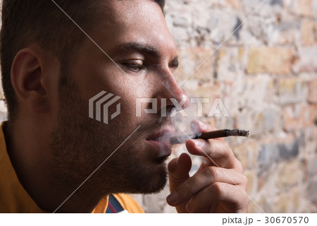 Young melancholic man exhaling cigarette smoke 30670570