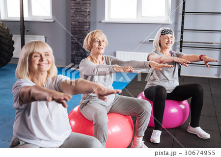 Joyful active women exercising on fitness balls Joyful active women exercising on fitness balls 30674955