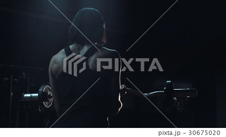 Strong toned young woman in a darkened gym 30675020