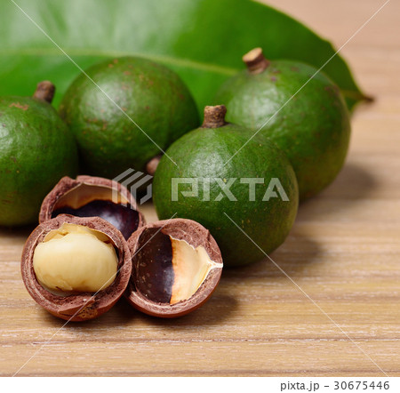 macadamia nuts isolated on wooden background 30675446