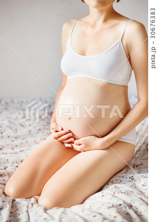 Pregnant woman in white underwear on bed. 30676383