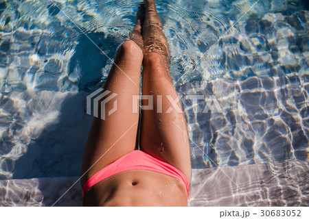 Female sexy tanned wet legs into water at pool. Female sexy tanned wet legs into water at pool. 30683052