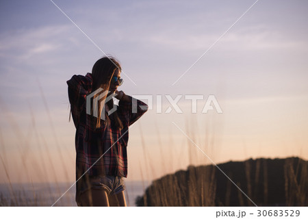 A girl stands on the edge of the cliff near the A girl stands on the edge of the cliff near the 30683529
