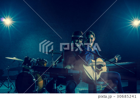 Musician duo band singing a song and playing music instrument with Fellow band musicians on black background with spot light and lens flare, musical concept 30685241