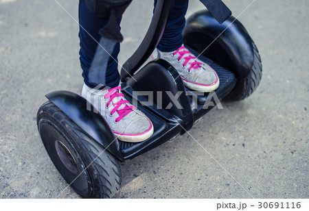 girl's legs wearing sneakers riding gyroscooter or girl's legs wearing sneakers riding gyroscooter or 30691116