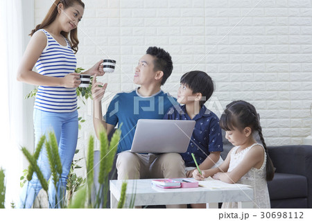 mother is giving water to father and son while daughter is drawing. 30698112