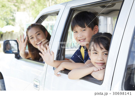 mother and two kids are waving to say good bye from the car. 30698141