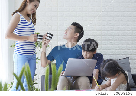 mother is giving water to father while kids are studying. 30698156