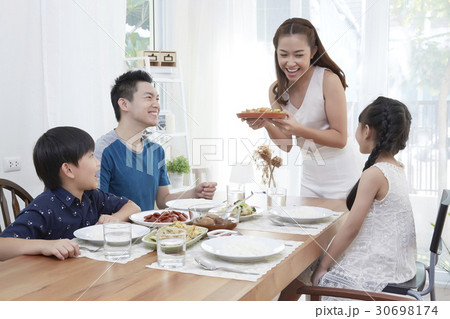 mom is taking food to the dining room for dad and two kids. 30698174