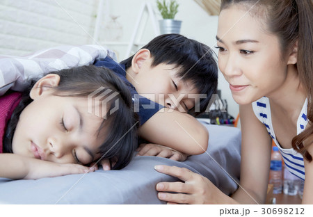 Mother is smiling while her children are sleeping. 30698212
