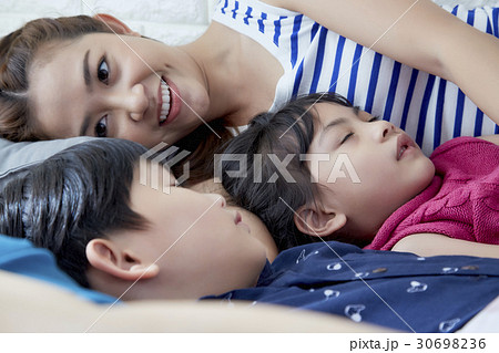Mother is smiling while her children are napping. 30698236