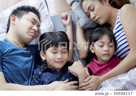Loving family is sleeping together in the bed. 30698237