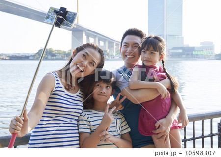 A photo of a happy family of four people taking selfie outdoor 30698307