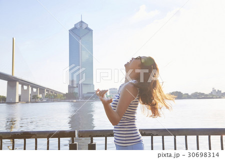 A girl is standing on a riverside, smiling and looking at the sky 30698314