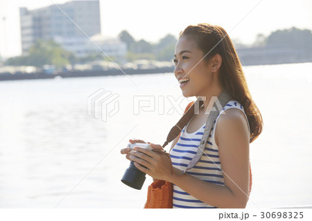 a photo of a girl smiling and holding a camera beside a river 30698325