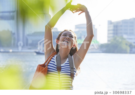 A girl is smiling and rising arms up beside a river. A girl is smiling and rising arms up beside a river. 30698337