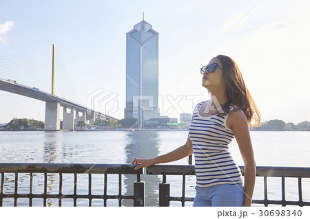 A girl with glasses is standing on a riverside and looking at the sky. A girl with glasses is standing on a riverside and looking at the sky. 30698340