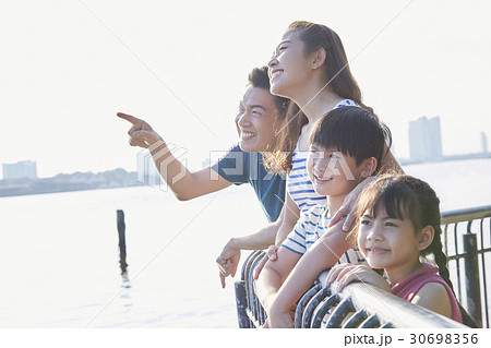 Parents and two kids are smiling and viewing on a riverside. Parents and two kids are smiling and viewing on a riverside. 30698356