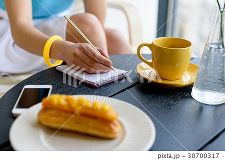 Elegant lady sitting at table and writing down her 30700317