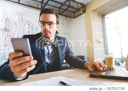 Calm businessman watching at mobile at desk Calm businessman watching at mobile at desk 30701730