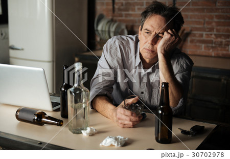 Portrait of upset man while holding empty glass 30702978