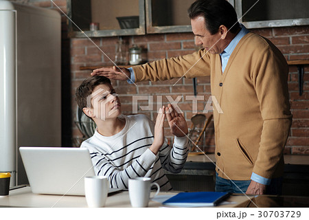 Kind male person holding right hand over head of 30703729