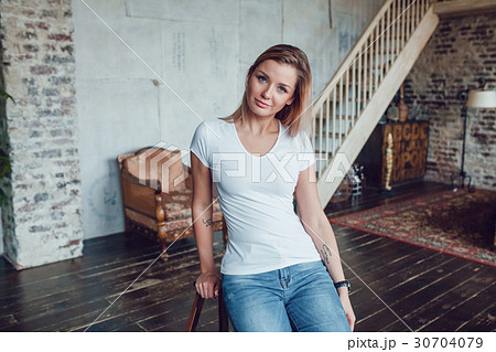 Attractive blonde woman in a white t-shirt sits at 30704079