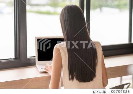 Back side of woman sitting and using computer laptop beside the 30704888
