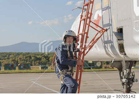 Military pilot in helmet stands near jet plane 30705142