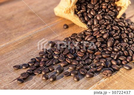 Roasted coffee beans in small sack on wooden table. Outdoor shooting with sunlight and blur background 30722437