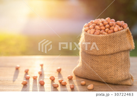 Peanut in small sack on wooden table. Outdoor shooting with sunlight and blur background 30722463
