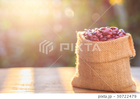 Red bean in small brown sack on wooden table. Outdoor shooting with sunlight and green blur bokeh and lens flare effect background 30722479