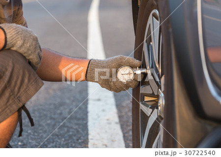Man checking air pressure and filling air in the tires of his car Man checking air pressure and filling air in the tires of his car 30722540