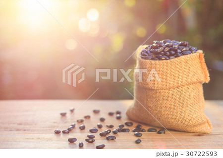 Black bean in small brown sack on wooden table. Outdoor shooting with sunlight and green blur bokeh and lens flare effect background 30722593