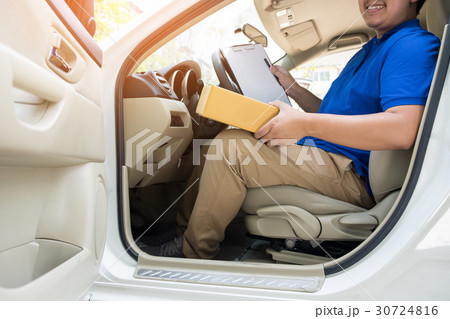 Delivery man with cardboard box checking document list In van an 30724816