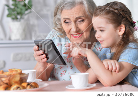 Grandmother with granddaughter playing in a tablet Grandmother with granddaughter playing in a tablet 30726686