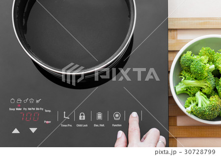 Woman switch on Induction stove 30728799