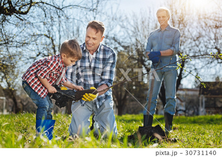 Senior gardener watching his son and grandchild 30731140