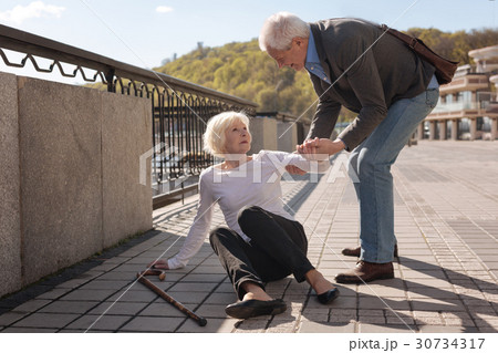 Friendly pensioner helping aged woman outdoors Friendly pensioner helping aged woman outdoors 30734317