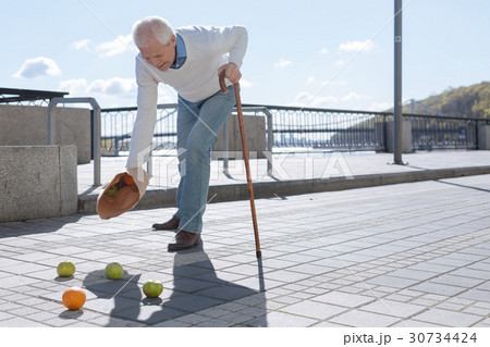 Aged man feeling pain in his arm outdoors Aged man feeling pain in his arm outdoors 30734424