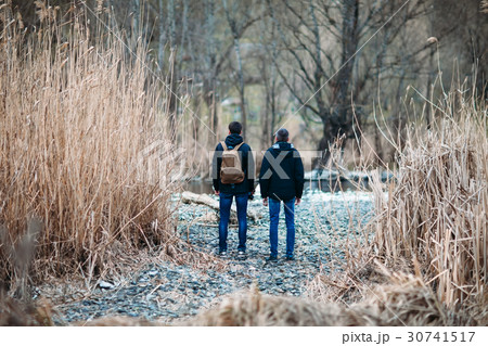 Back view of men standing on road in forest Back view of men standing on road in forest 30741517