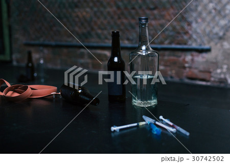 Bottles full of alcohol and syringes lying on the 30742502