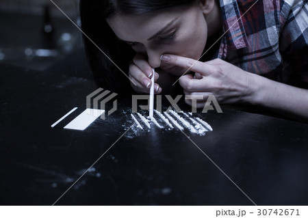 Drug addict snorting heroin lines in the dark 30742671