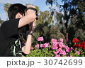 花の前で写真撮影をしている男性 30742699