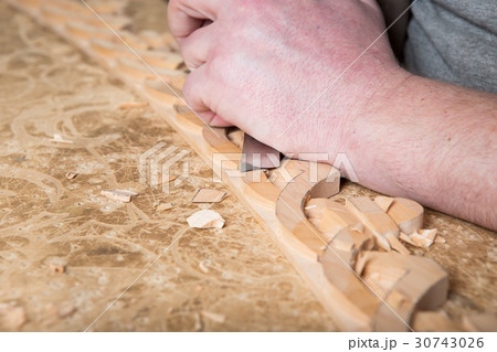 woodcarver creates a furniture ornament.  30743026
