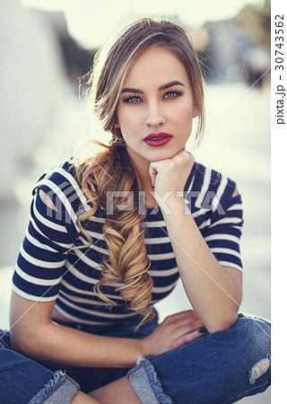 Blonde woman, model of fashion, sitting in urban background. Blonde woman, model of fashion, sitting in urban background. 30743562