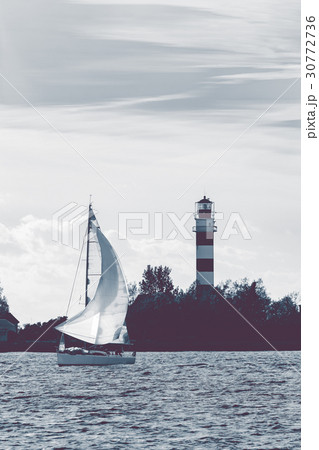 Sailboat moving past lighthouse 30772736